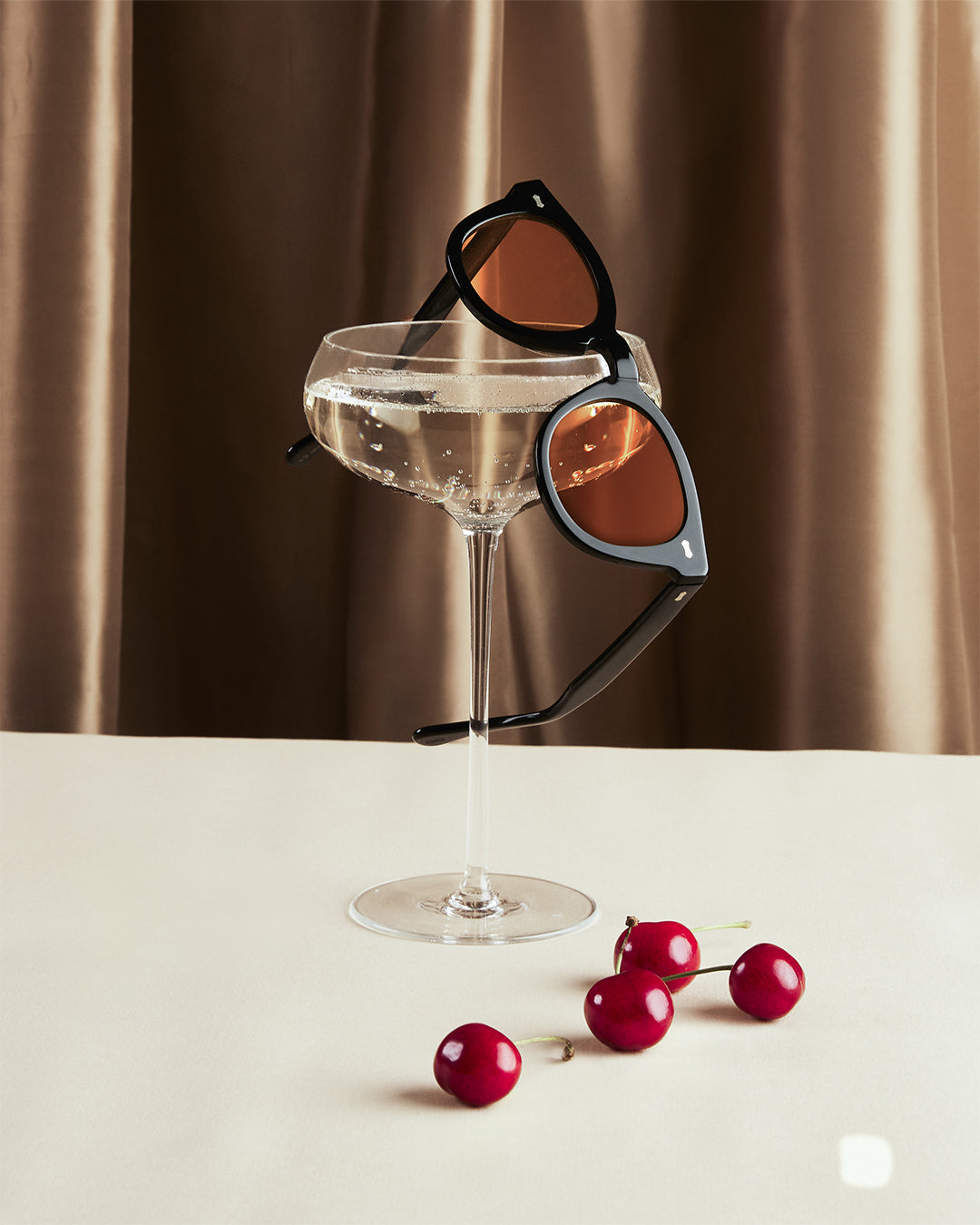 Sunglasses on a cocktail glass with cherries on a neutral background. - DEI DUCHI