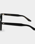 Black sunglasses with green lenses on a light gray background. - Dei Duchi
