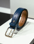 Blue leather belt with a gold buckle on a white surface. - Sartoria Dei Duchi-Atri