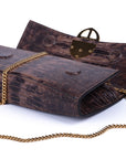 Brown embossed python skin clutch bag with gold chain and buckle/emblem on a white background. - DEI DUCHI (AMALTEA)