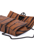 Brown leather wallet with chain strap
and embossed tiger stripe pattern and burnished metal buckle clasp on a white background. -DEI DUCHI (AMALTEA)