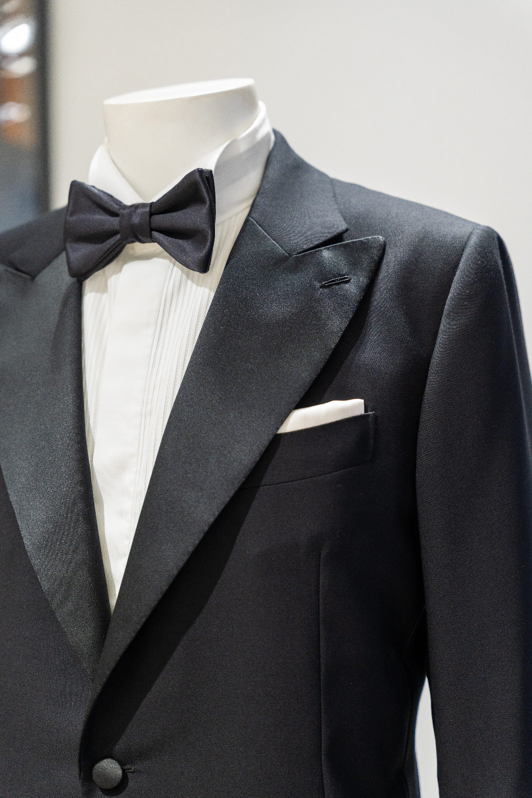 Black tuxedo with bow tie on a mannequin against a neutral background. - Sartoria Dei Duchi-Atri