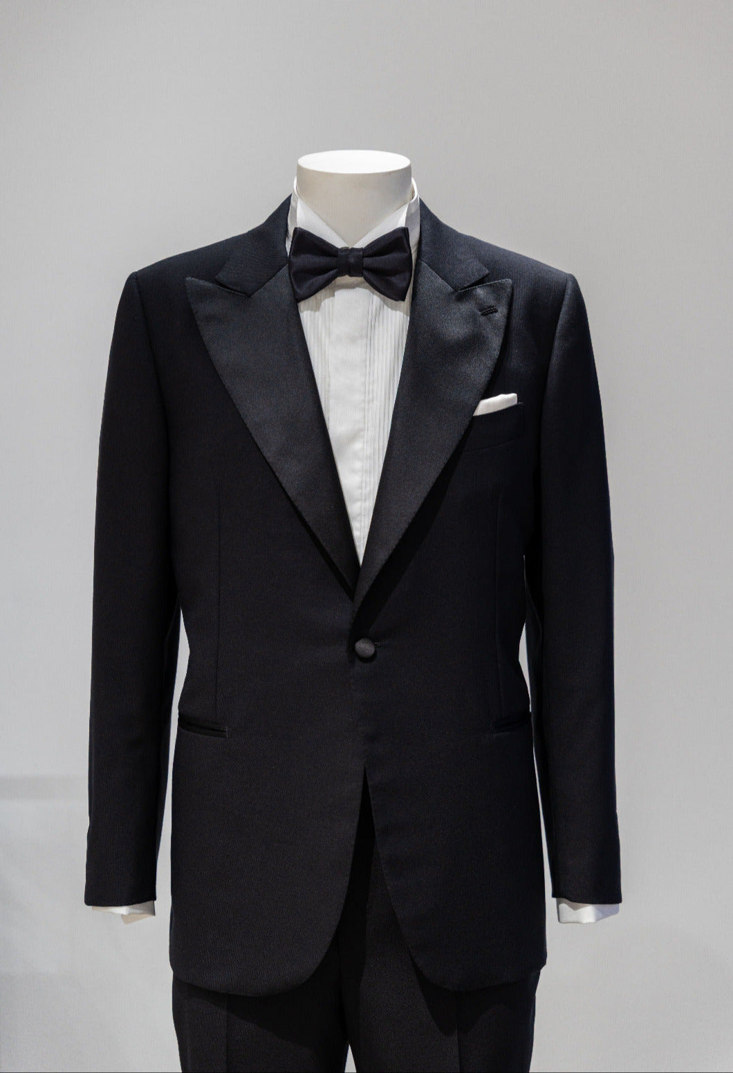 Black tuxedo with bow tie on a mannequin against a gray background. - Sartoria Dei Duchi-Atri