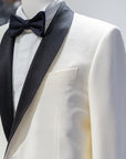 White tuxedo jacket with black lapels and bow tie on a mannequin against a gray background. - Sartoria Dei Duchi-Atri