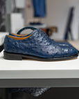 Blue textured dress shoe on a white surface with a blurred background. Sartoria Dei Duchi-Atri