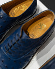 Close-up of blue dress shoes with gold insole text on a white background. - Sartoria Dei Duchi-Atri