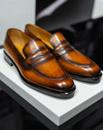 Pair of brown leather loafers on a white platform. - Sartoria Dei Duchi-Atri
