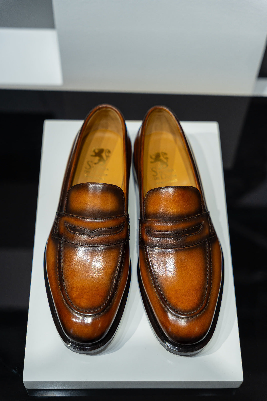 Pair of brown leather loafers on a white platform. - Sartoria Dei Duchi-Atri