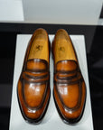 Pair of brown leather loafers on a white platform. - Sartoria Dei Duchi-Atri