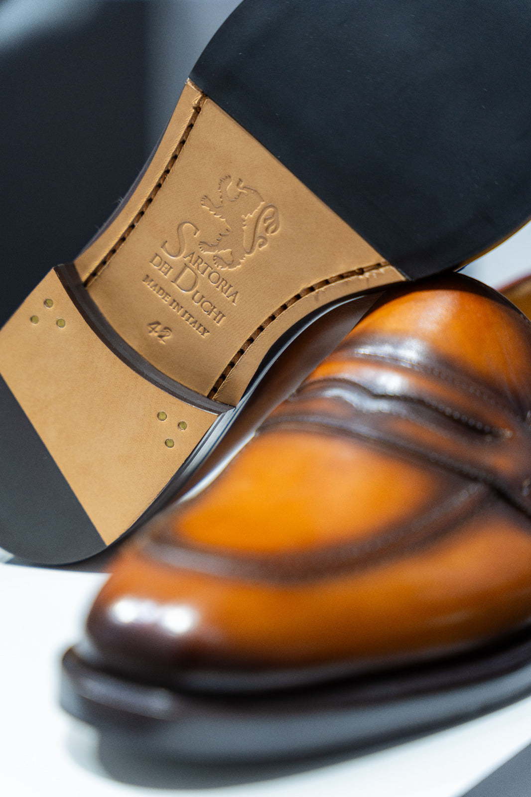 Pair of brown leather loafers on a white platform. - Sartoria Dei Duchi-Atri