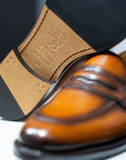 Pair of brown leather loafers on a white platform. - Sartoria Dei Duchi-Atri