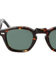 Sunglasses with tortoiseshell frame and green lenses on a light gray background. - Dei Duchi