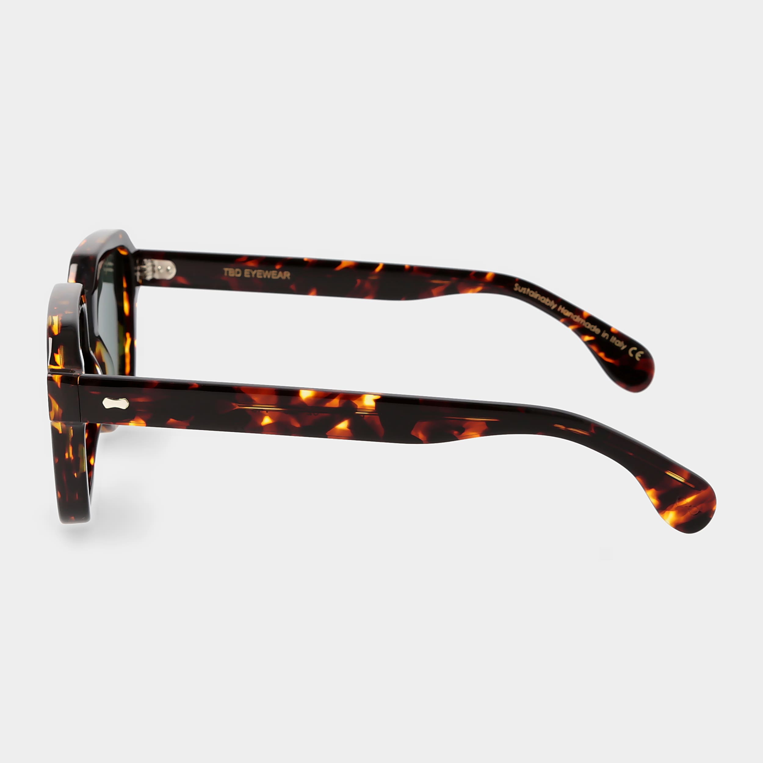 Sunglasses with tortoiseshell frame and green lenses on a light gray background. _ DEI DUCHI