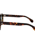 Sunglasses with tortoiseshell frame and green lenses on a light gray background. _ DEI DUCHI