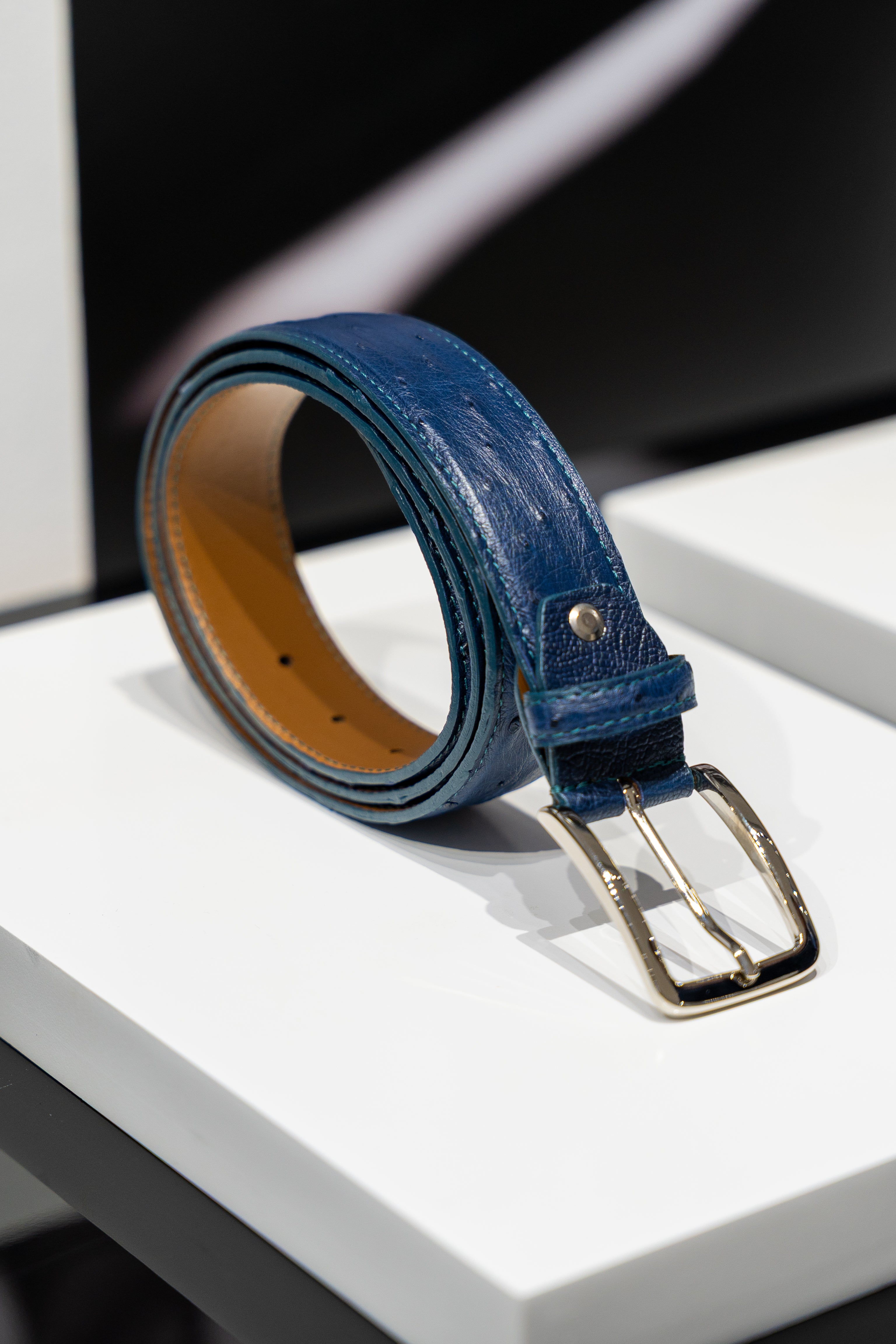 Blue leather belt with a gold buckle on a white surface. - Sartoria Dei Duchi-Atri