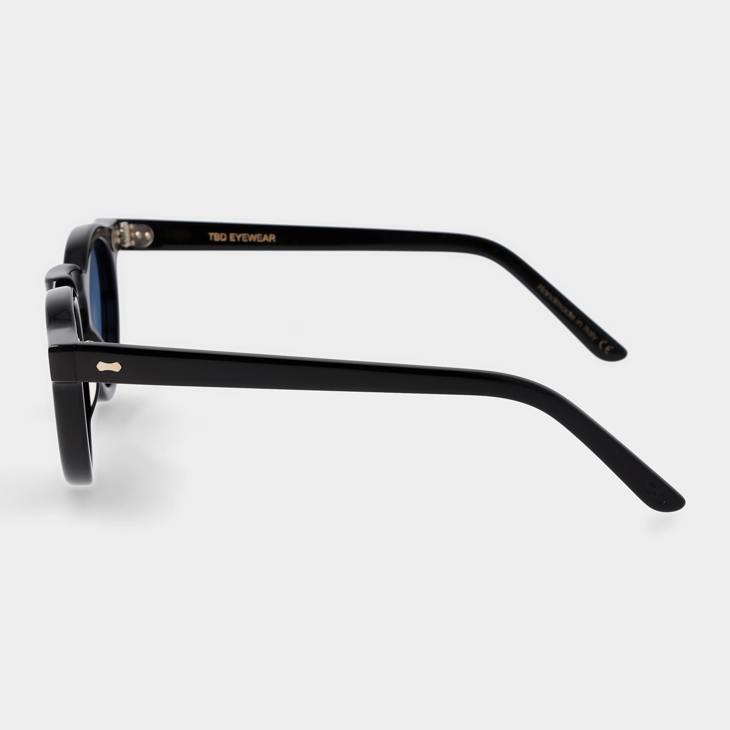 Round sunglasses with black frames and blue lenses on a light gray background. -DEI DUCHI