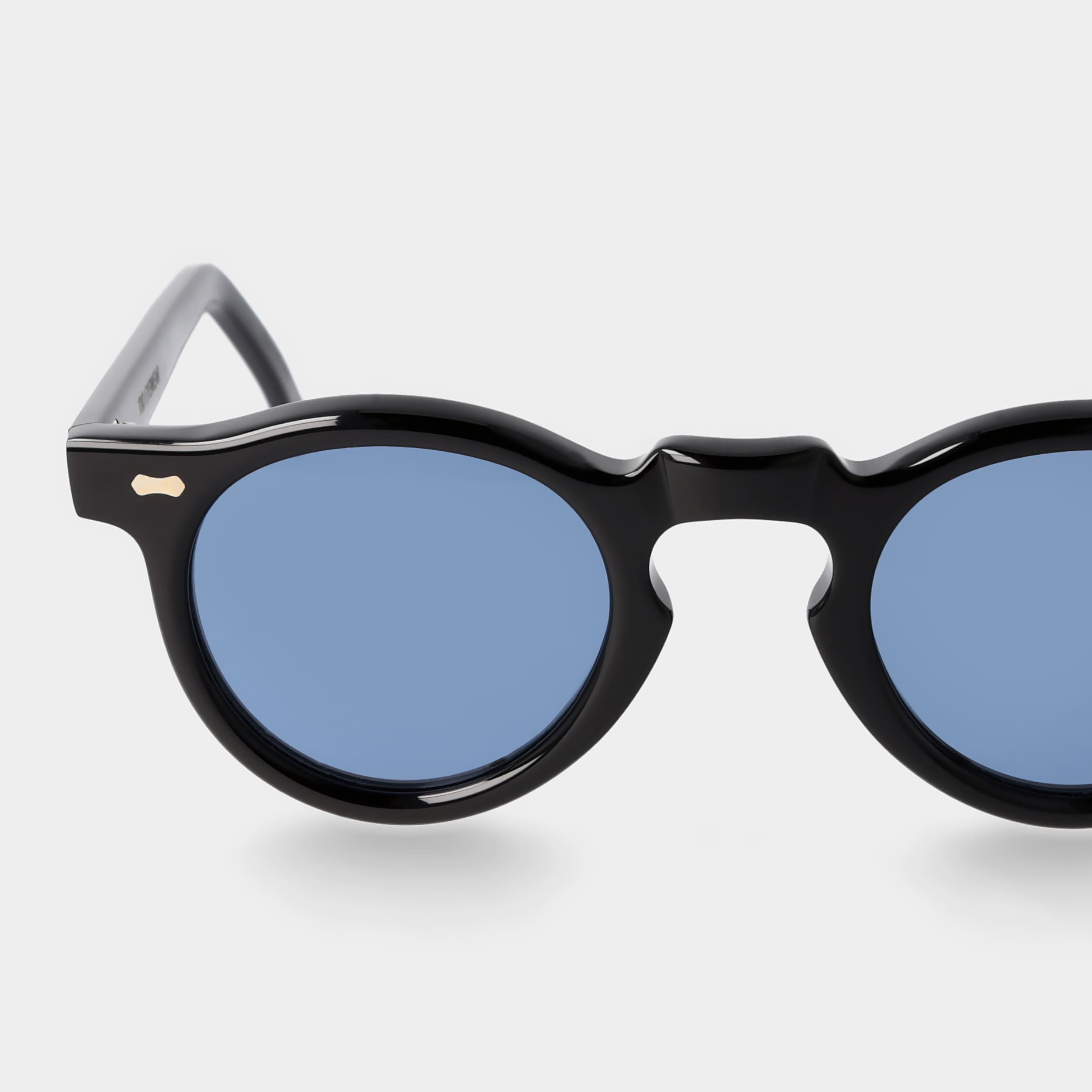 Round sunglasses with black frames and blue lenses on a light gray background. -DEI DUCHI
