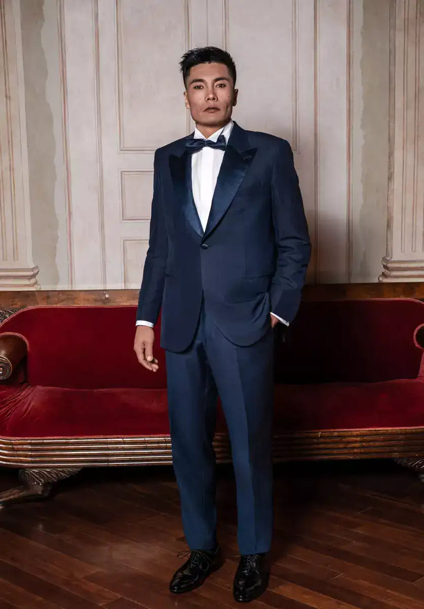 THE JACKET: Single-breasted jacket with one button. Peak lapel in silk satin. Classic pockets. Buttons lined in silk satin, double slit on the back. Button holes, pockets, undercollar and all finishing touches, are handmade by Italian tailors, with the sweet touch of a blue bow-tie.The TROUSER: not the usual classic silk satin band, but a Trouser that have a Silk satin belt,instead. Without pleats, slim, with internal buttons for suspenders.Also available in black color.|Sartoria Dei Duchi-Atri