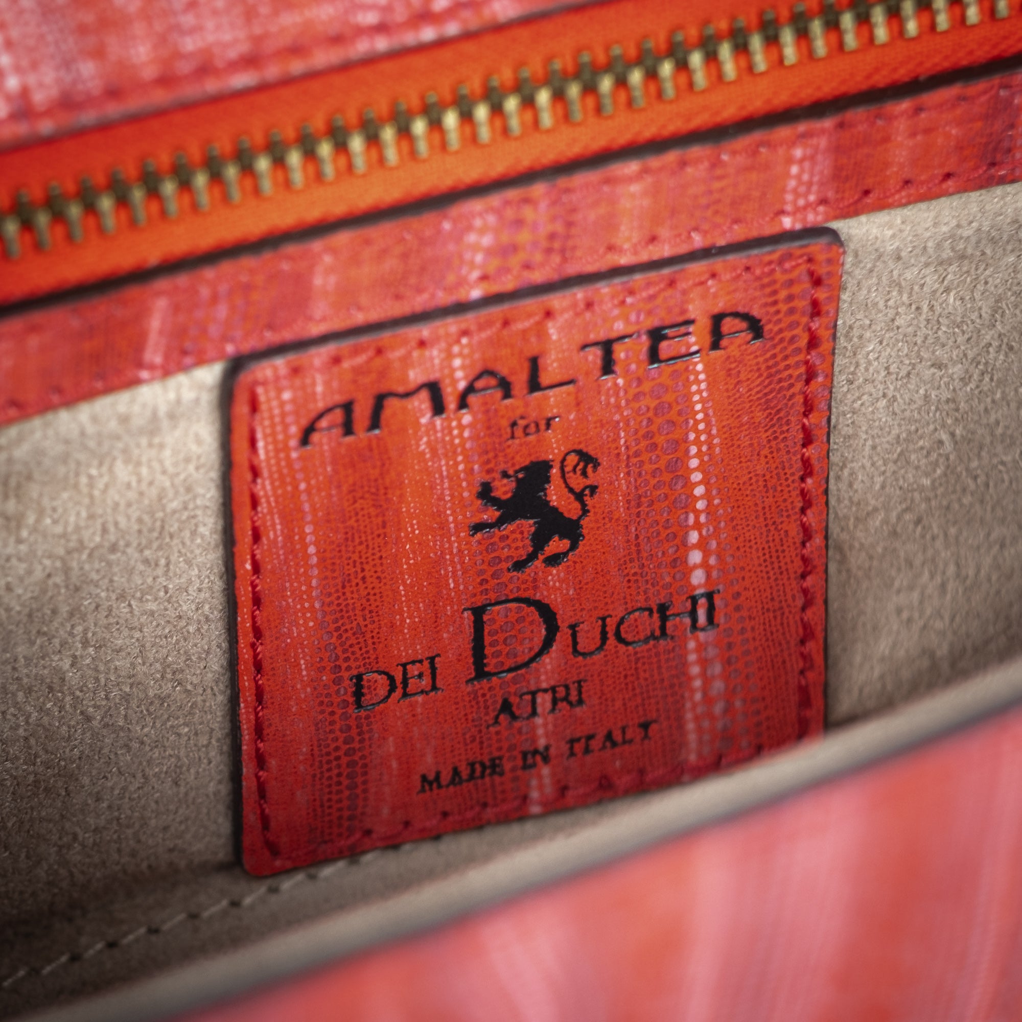 Red handbag with a chain detail, Red clutch bag with a gold emblem on a white background - DEI DUCHI (ALMATEA)