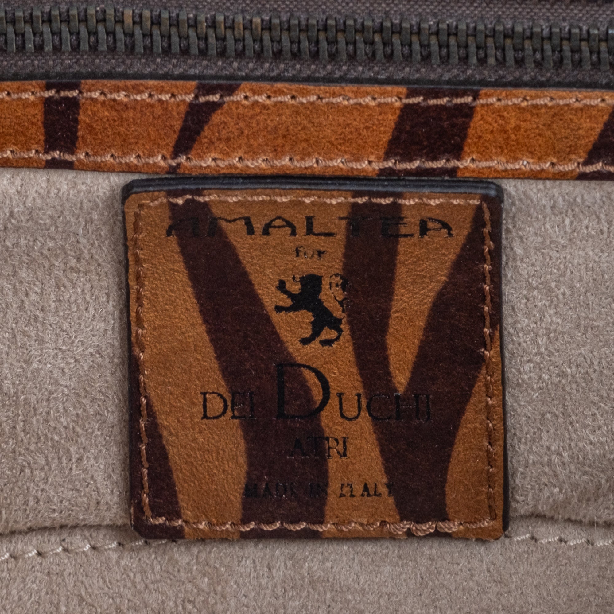 Brown leather wallet with chain strap 
 and embossed tiger stripe pattern and burnished metal buckle clasp on a white background.  -DEI DUCHI (AMALTEA)