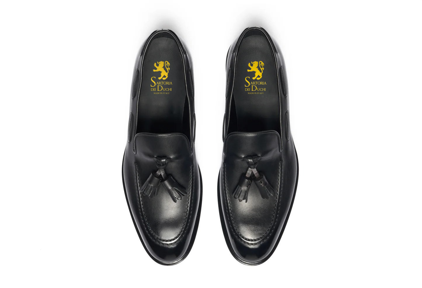 Pair of black loafers with a visible brand logo on a white background. Crust Calf. White full/grain calfskin. Tuscan tanned. Hand-dyed and antiqued leather. 9mm sole. 27mm heel height. Tuscan leather. Blake construction with bottom stitching. - Sartoria Dei Duchi - Atri