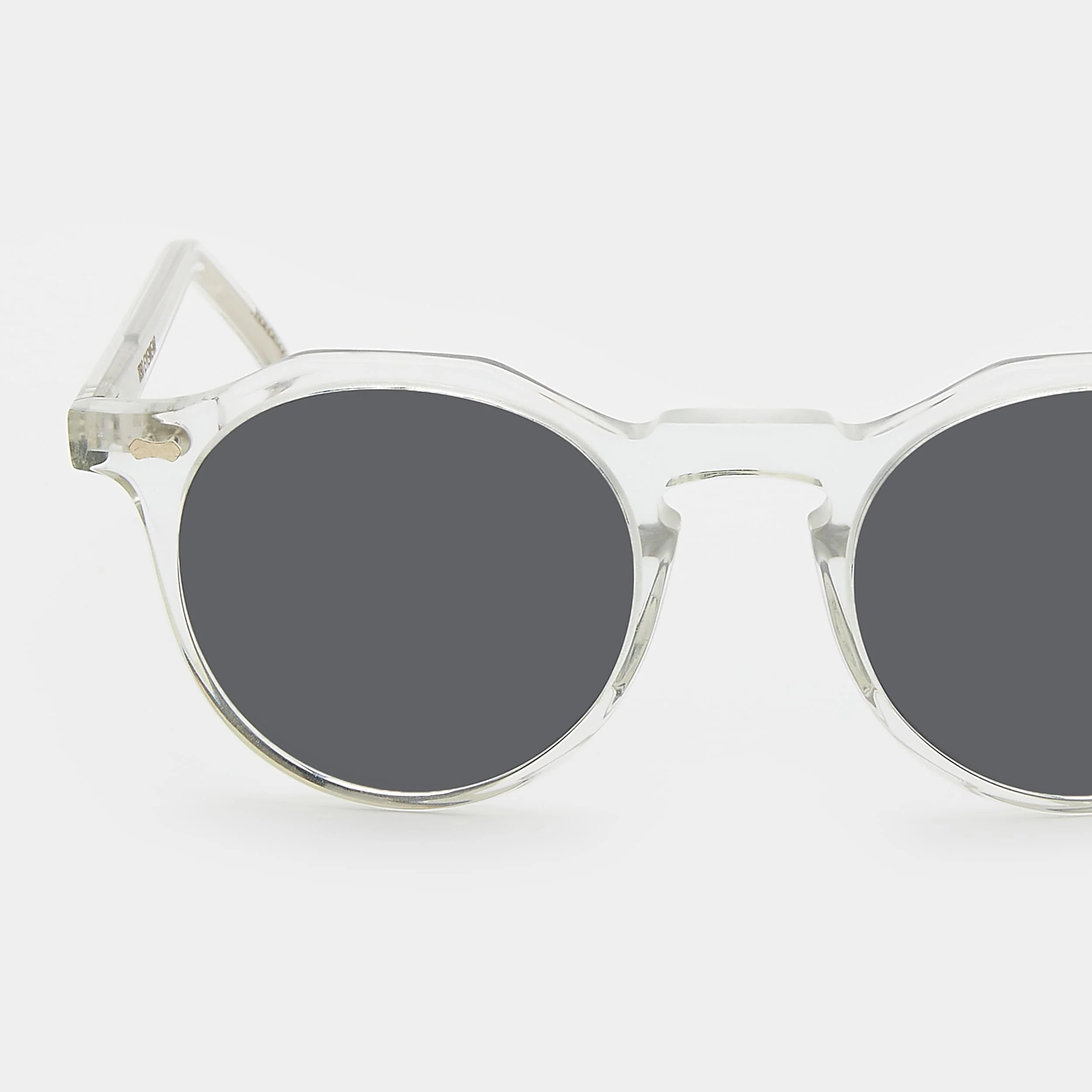 Round sunglasses with clear frame and dark lenses on a white background. - DEI DUCHI