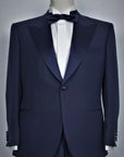 THE JACKET: Single-breasted jacket with one button. Peak lapel in silk satin. Classic pockets. Buttons lined in silk satin, double slit on the back. Button holes, pockets, undercollar and all finishing touches, are handmade by Italian tailors, with the sweet touch of a blue bow-tie.The TROUSER: not the usual classic silk satin band, but a Trouser that have a Silk satin belt,instead. Without pleats, slim, with internal buttons for suspenders.Also available in black color.|Sartoria Dei Duchi-Atri