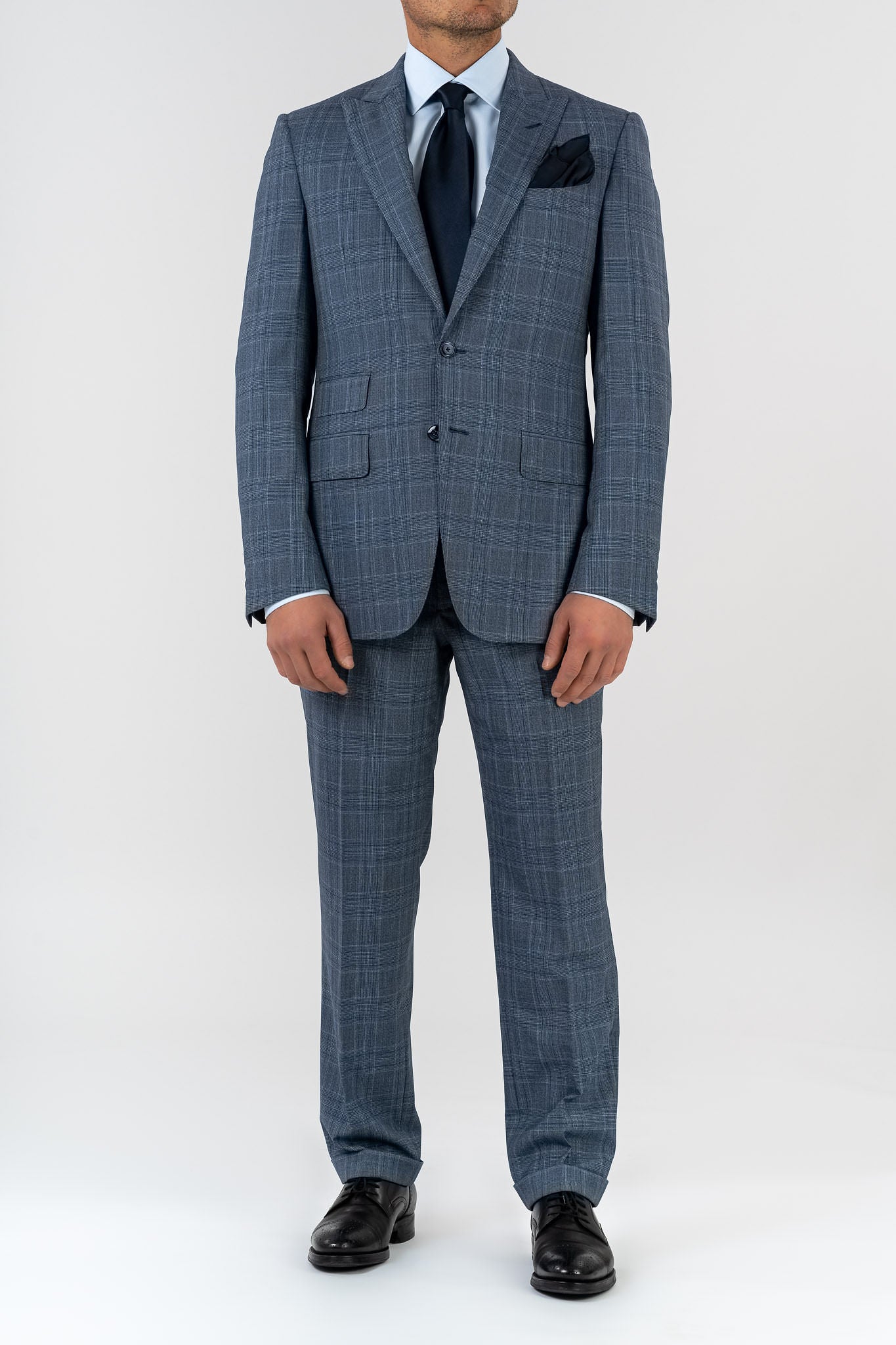 This elegant suit is made with 100% pure merino wool “Super 170s WISH” by Loro Piana. It is characterized by a checked design in shades of gray and light blue. This is a two-piece with two-button jacket with 3 pockets with flaps. One of these pockets is a watch pocket. The pants has regular rise and no darts, with american cut pockets and two back pockets. Belt with loops and zip on the front. -  Sartoria dei Duchi.