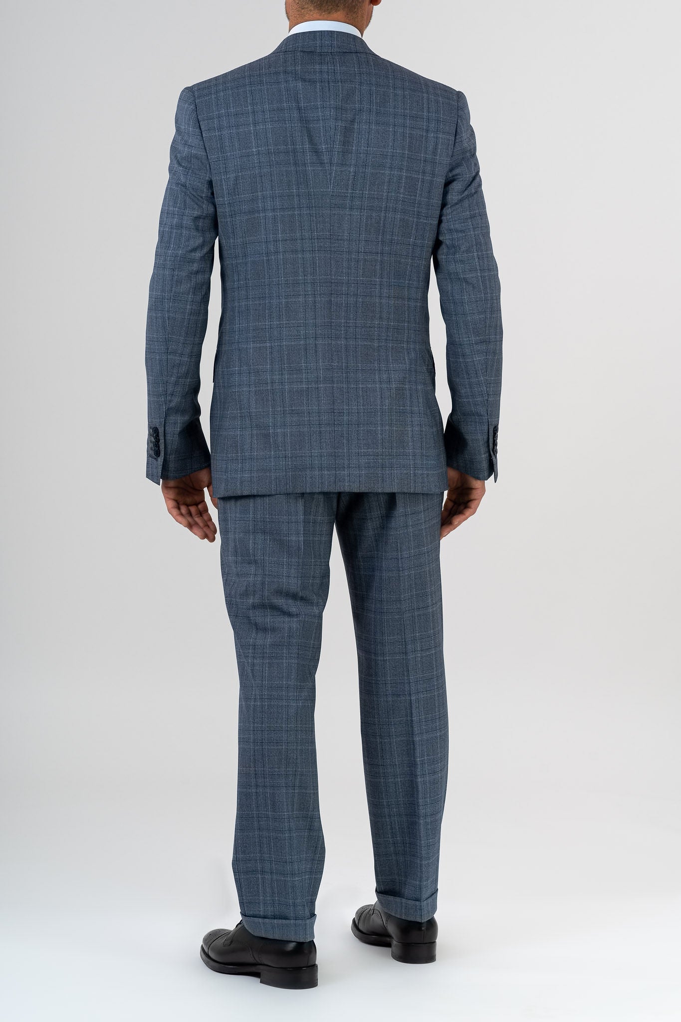 This elegant suit is made with 100% pure merino wool “Super 170s WISH” by Loro Piana. It is characterized by a checked design in shades of gray and light blue. This is a two-piece with two-button jacket with 3 pockets with flaps. One of these pockets is a watch pocket. The pants has regular rise and no darts, with american cut pockets and two back pockets. Belt with loops and zip on the front. -  Sartoria dei Duchi.