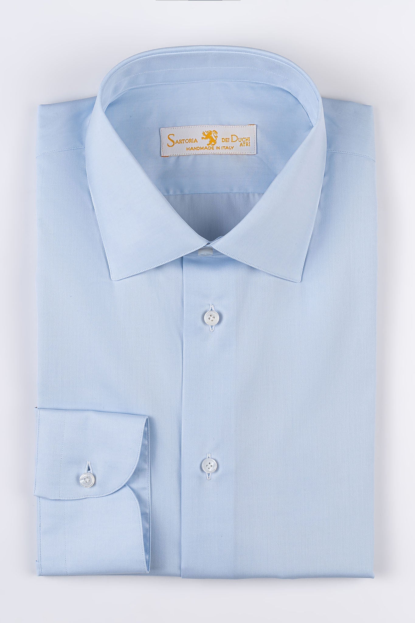 Our “HAMPTON SHIRT” is realized with a 140/2 cotton twill by Thomas Mason &quot;Hampton&quot;, in light blue color. This long sleeve shirt is made with a semi French collar and a rounded wrist. The stitching is 5 mm and the buttons, applied by hand, are in mother of pearl Australia.  The fit is regular. - Sartoria Dei Duchi-Atri