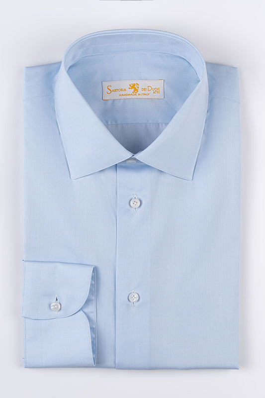 Our “HAMPTON SHIRT” is realized with a 140/2 cotton twill by Thomas Mason "Hampton", in light blue color. This long sleeve shirt is made with a semi French collar and a rounded wrist. The stitching is 5 mm and the buttons, applied by hand, are in mother of pearl Australia.  The fit is regular. - Sartoria Dei Duchi-Atri