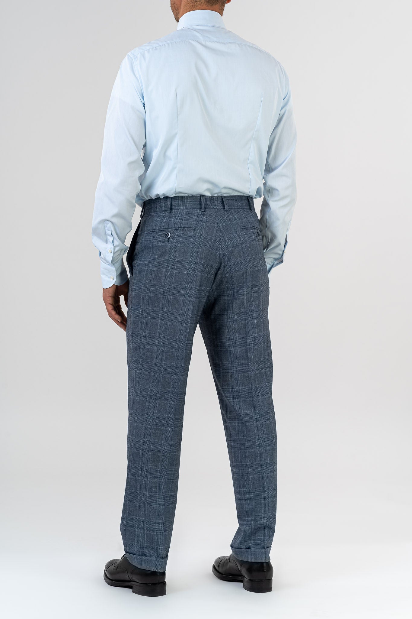 This elegant suit is made with 100% pure merino wool “Super 170s WISH” by Loro Piana. It is characterized by a checked design in shades of gray and light blue. This is a two-piece with two-button jacket with 3 pockets with flaps. One of these pockets is a watch pocket. The pants has regular rise and no darts, with american cut pockets and two back pockets. Belt with loops and zip on the front. -  Sartoria dei Duchi.