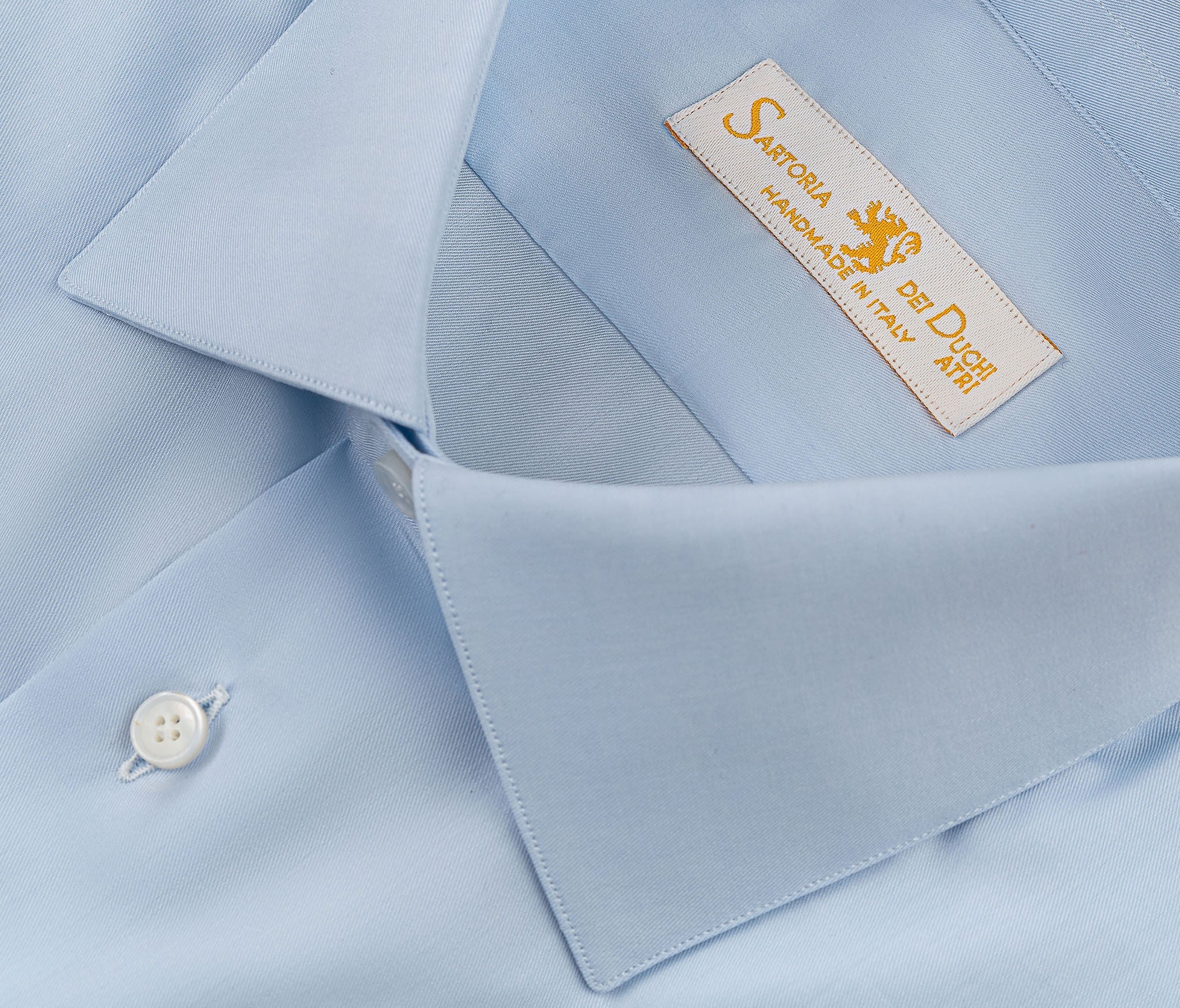 Our “HAMPTON SHIRT” is realized with a 140/2 cotton twill by Thomas Mason "Hampton", in light blue color. This long sleeve shirt is made with a semi French collar and a rounded wrist. The stitching is 5 mm and the buttons, applied by hand, are in mother of pearl Australia.  The fit is regular. - Sartoria Dei Duchi-Atri